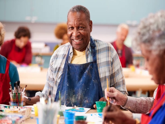 Smiling senior man wearing apron painting ceramics